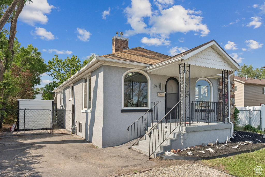 View of front of home featuring a gate, a chimney, and stucco siding