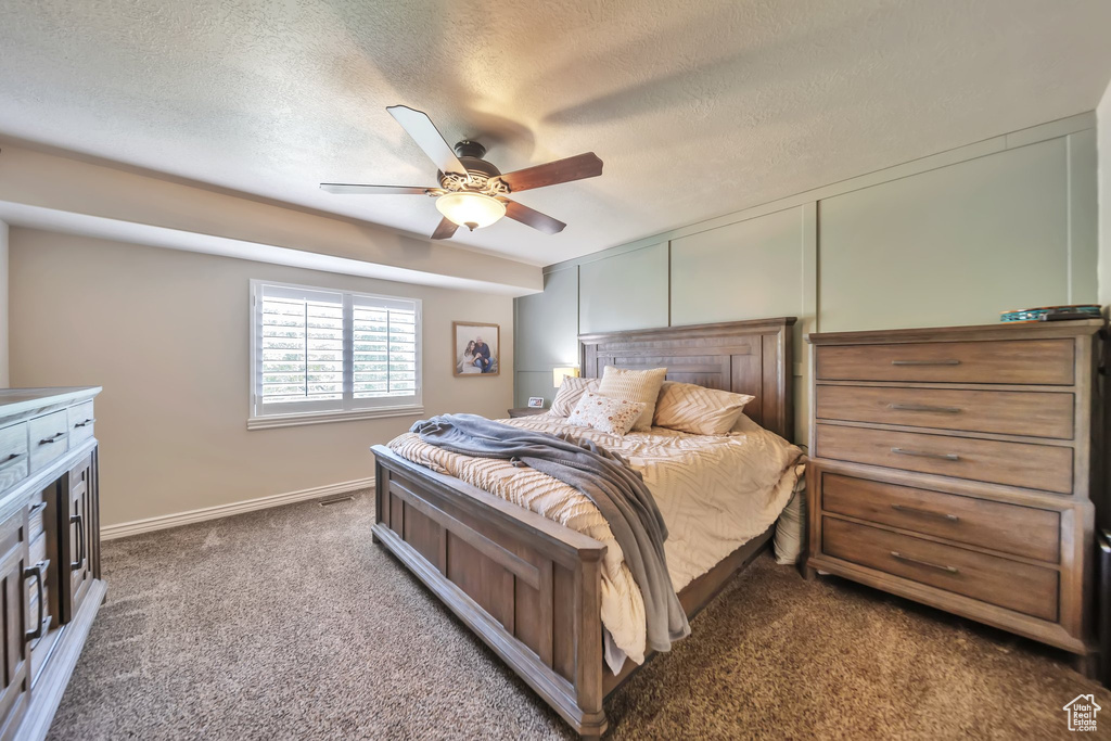 Carpeted bedroom featuring a textured ceiling and ceiling fan