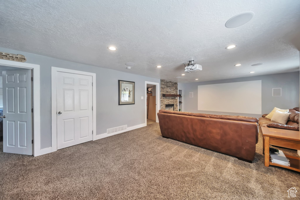 Carpeted cinema featuring a stone fireplace, a textured ceiling, and recessed lighting