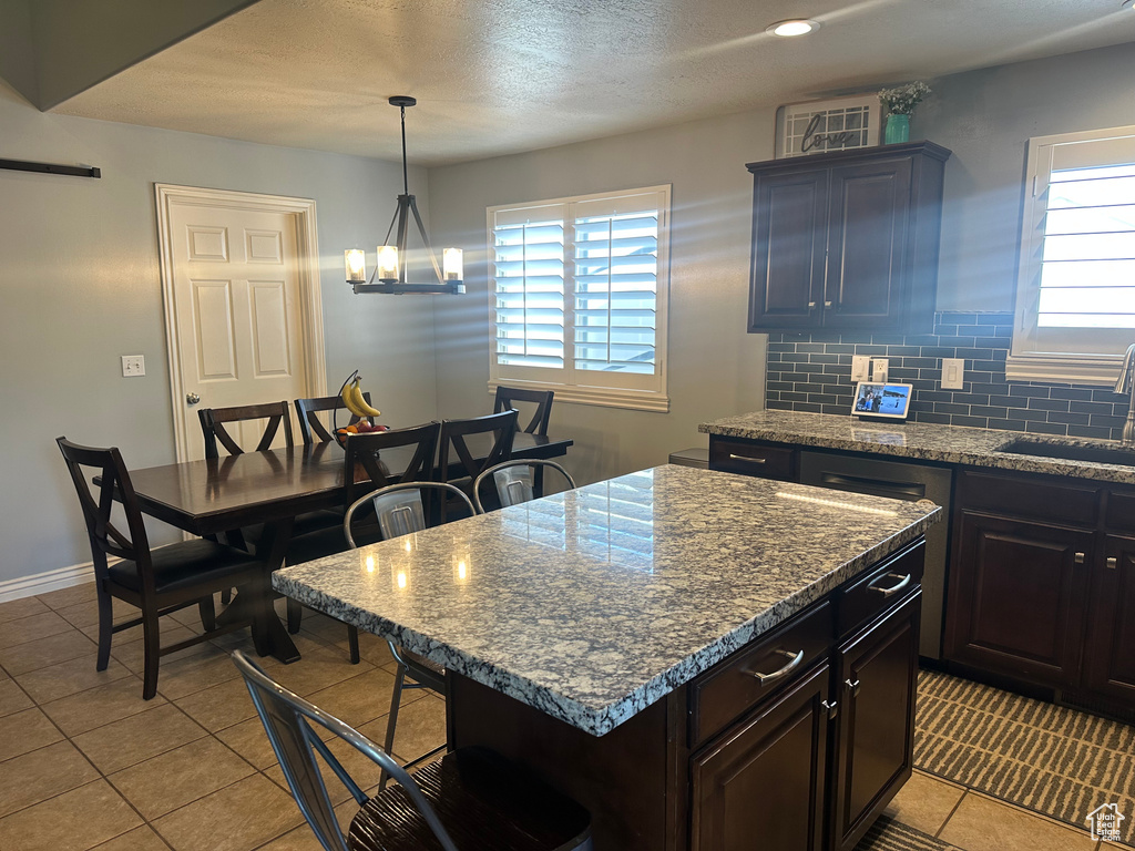 Kitchen with healthy amount of natural light, light tile patterned floors, a breakfast bar, a kitchen island, and a textured ceiling