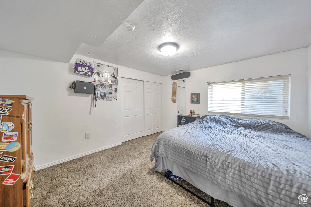 Bedroom with carpet floors, a textured ceiling, and a closet