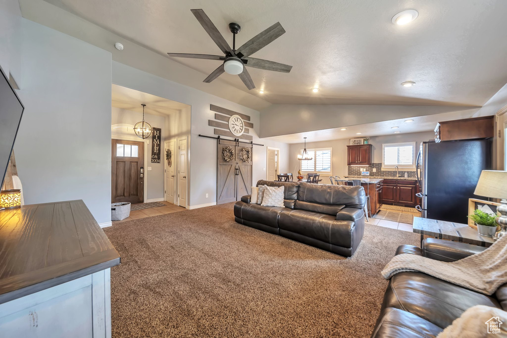 Living area featuring a barn door, vaulted ceiling, light carpet, ceiling fan, and recessed lighting