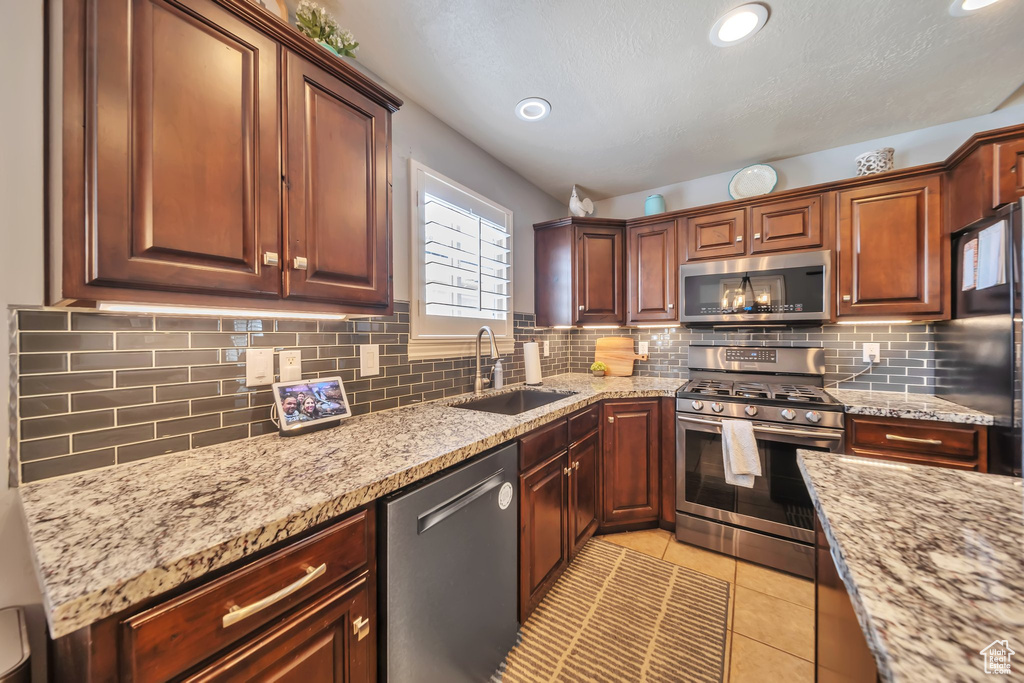 Kitchen featuring appliances with stainless steel finishes, decorative backsplash, light stone countertops, and recessed lighting