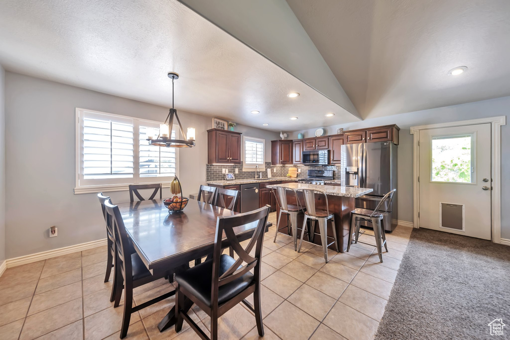Dining area featuring light tile patterned flooring, recessed lighting, a chandelier, and vaulted ceiling