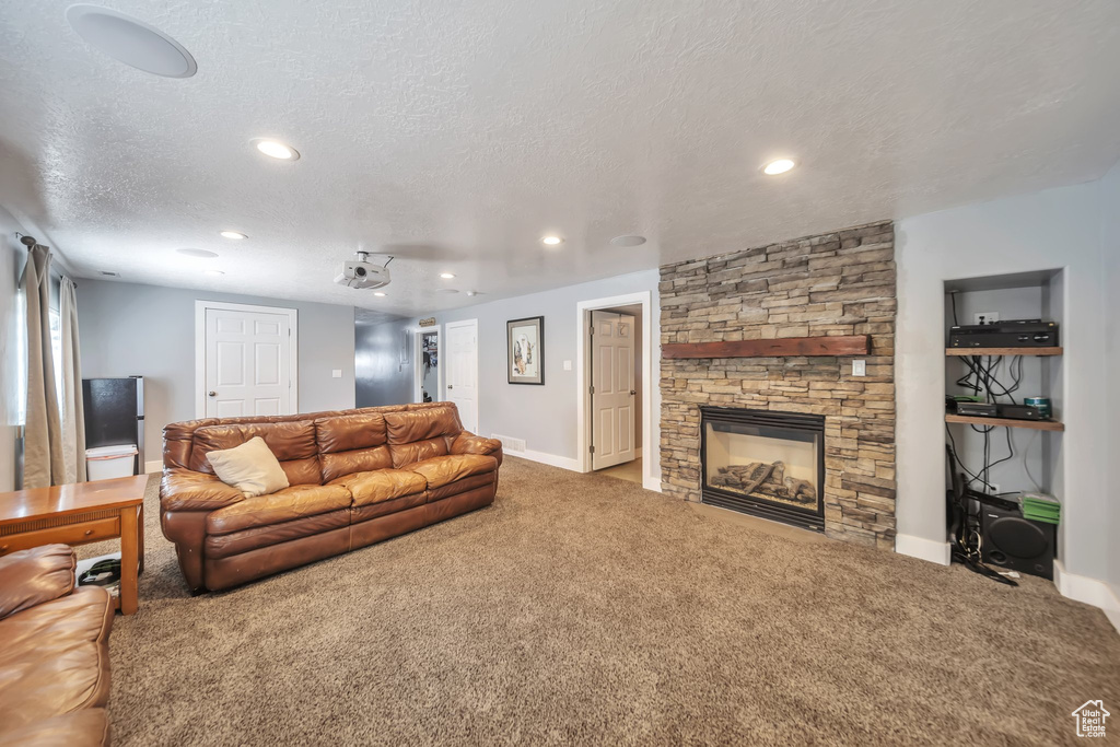 Living area featuring carpet flooring, recessed lighting, a stone fireplace, and a textured ceiling