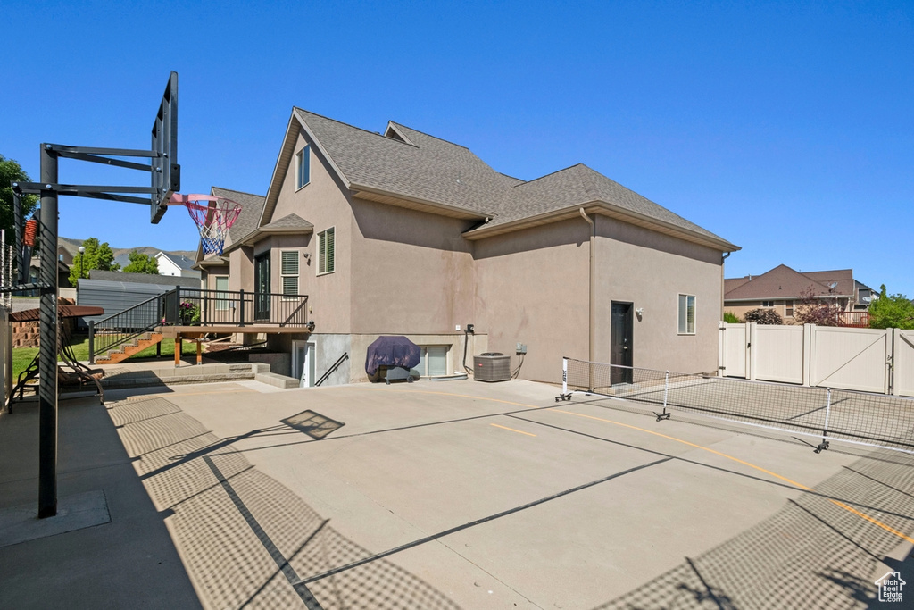 Rear view of house featuring stucco siding and a tennis court