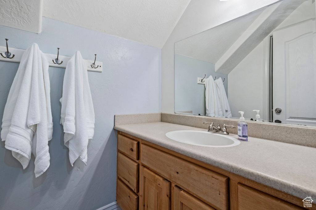 Bathroom featuring vaulted ceiling and vanity