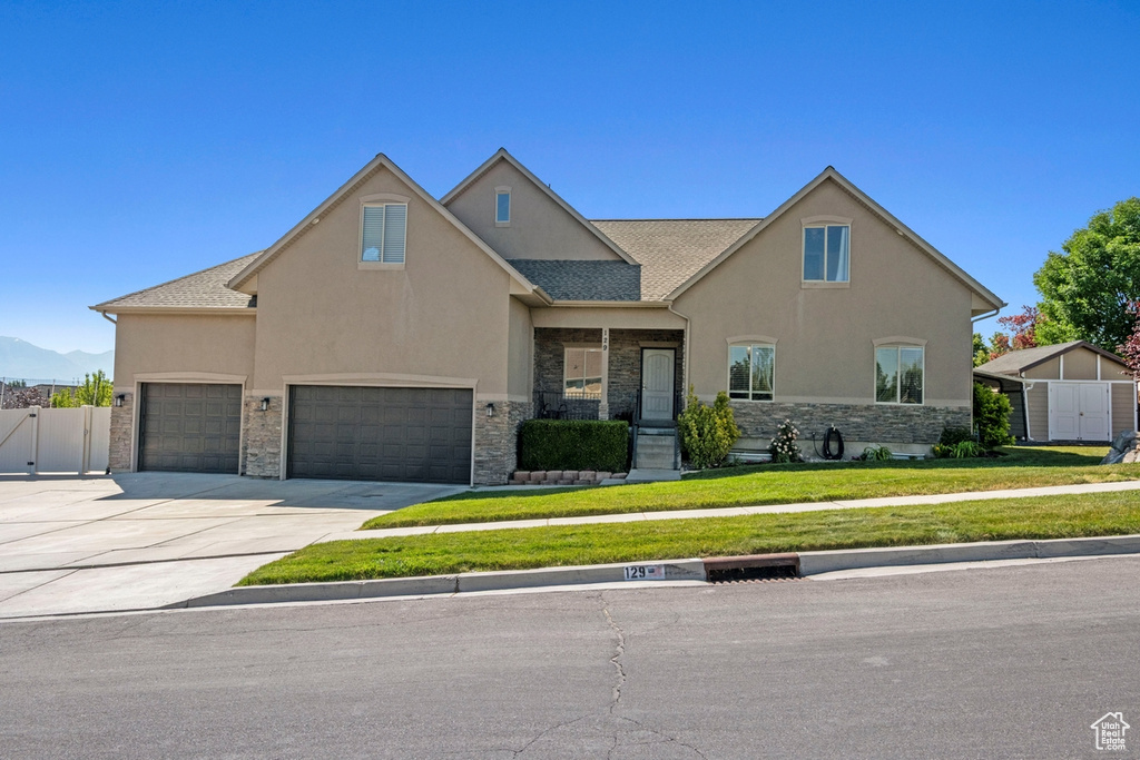 View of front facade with stone siding, stucco siding, concrete driveway, and an attached garage