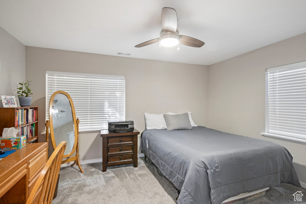Bedroom with light colored carpet and a ceiling fan