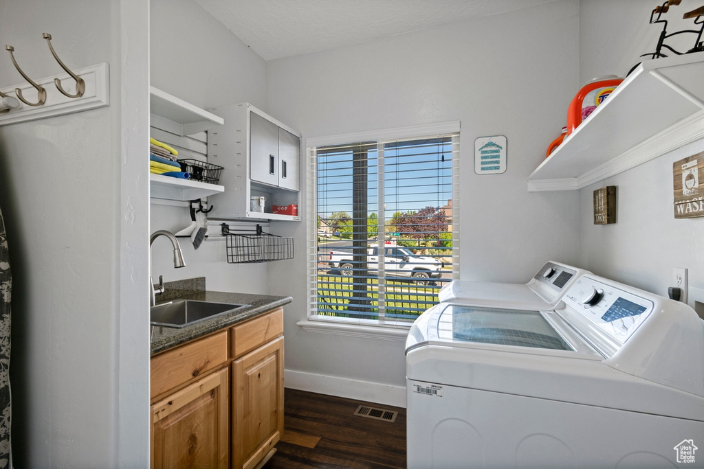 Washroom with washing machine and clothes dryer, dark wood-type flooring, healthy amount of natural light, and cabinet space