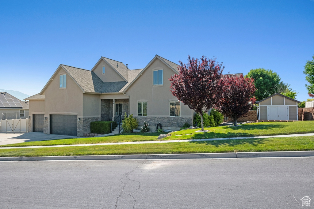 View of front of home featuring stone siding, stucco siding, a garage, and asphalt driveway