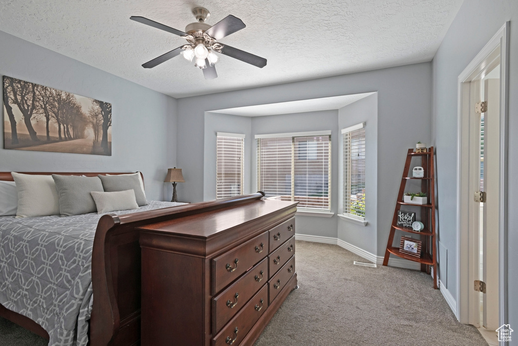 Bedroom featuring light colored carpet, a textured ceiling, and ceiling fan