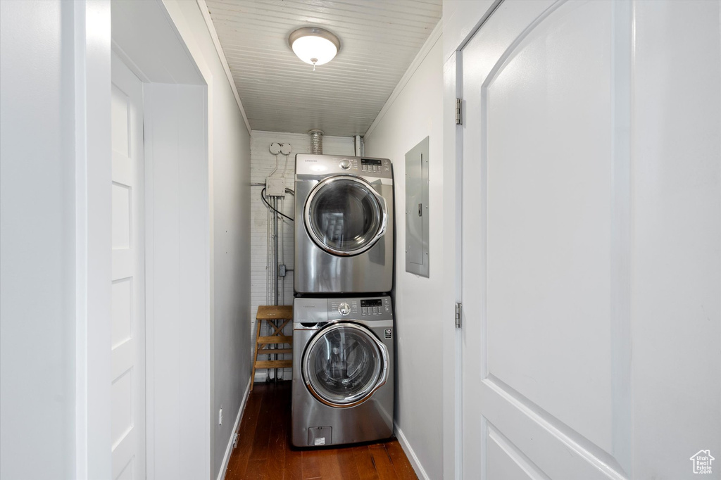 Laundry area featuring estacked washer and dryer, dark wood-style flooring, and electric panel