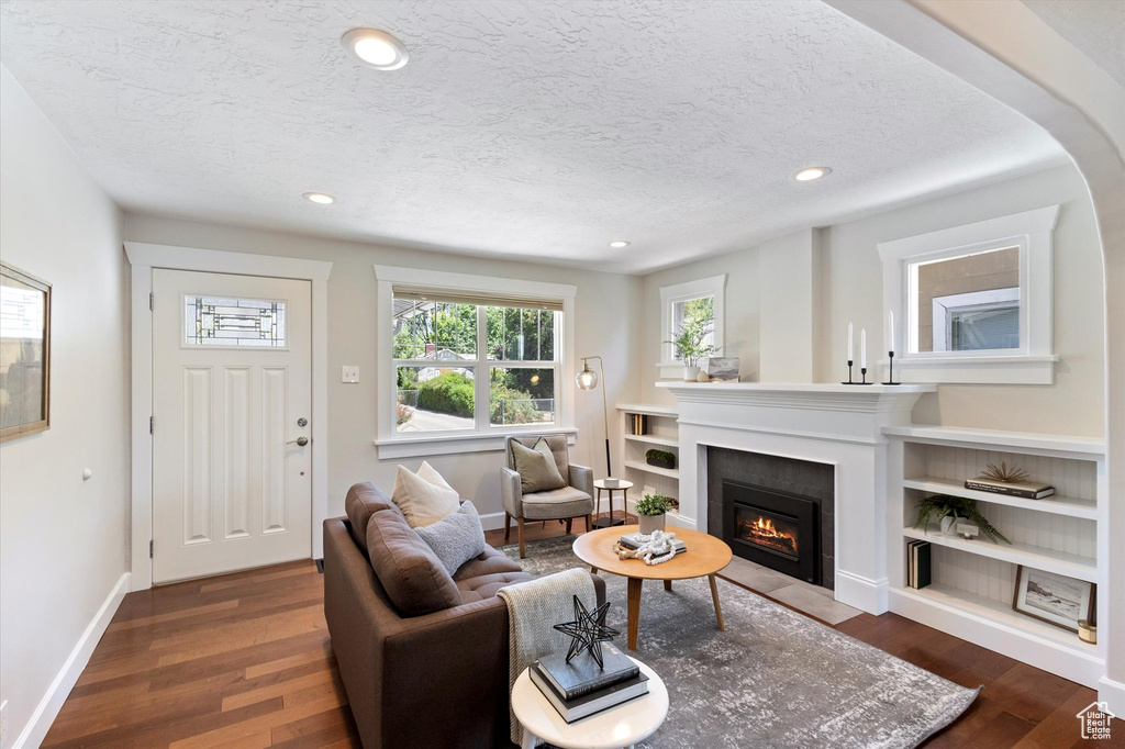 Living area with a textured ceiling, recessed lighting, dark wood-style floors, and a fireplace with flush hearth