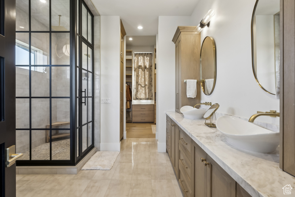 Full bath featuring double vanity, tiled shower, a walk in closet, tile patterned flooring, and recessed lighting