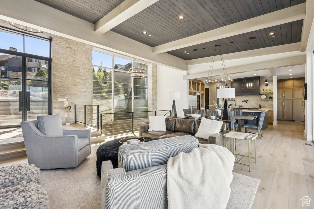 Living area featuring light wood-style flooring and a wooden ceiling with exposed beams