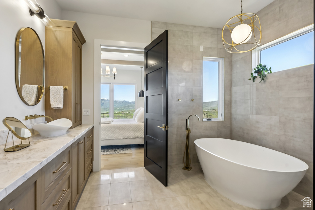 Full bath with a chandelier, ensuite bathroom, vanity, tile walls, and a freestanding tub