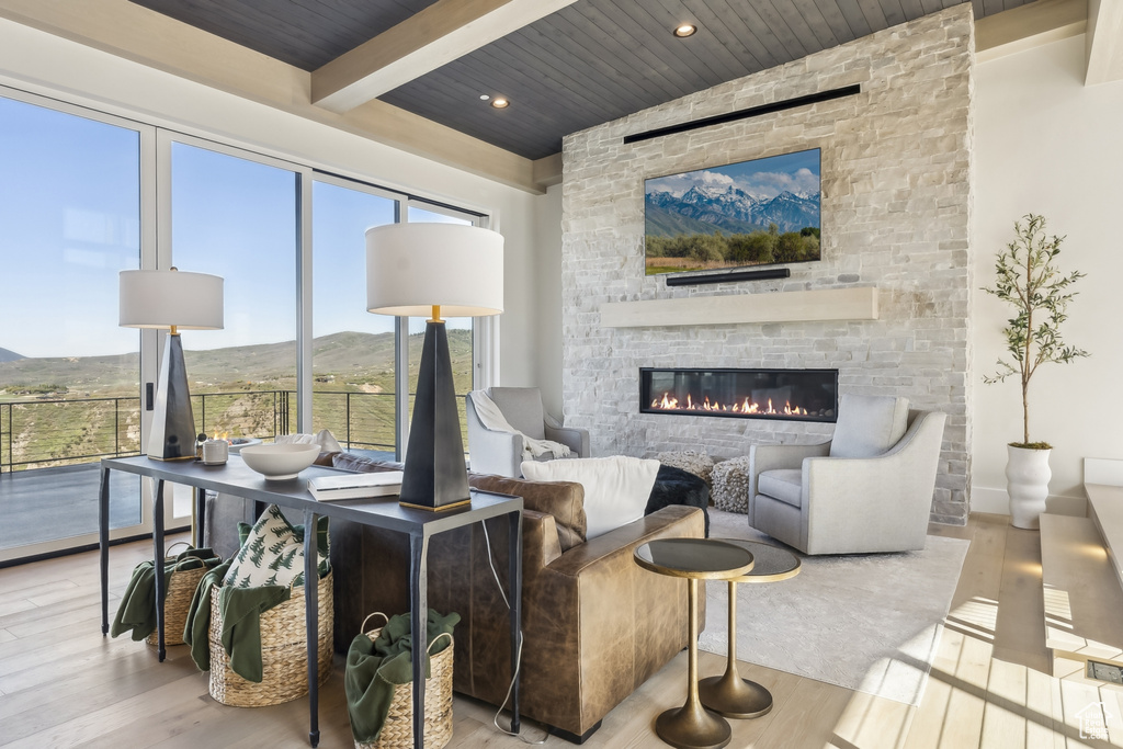 Living room with wood finished floors, a fireplace, and a wood ceiling with exposed beams