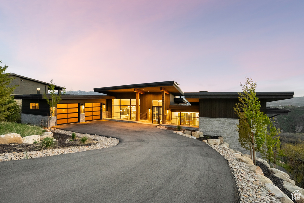 View of front of home featuring a garage, stone siding, and asphalt driveway