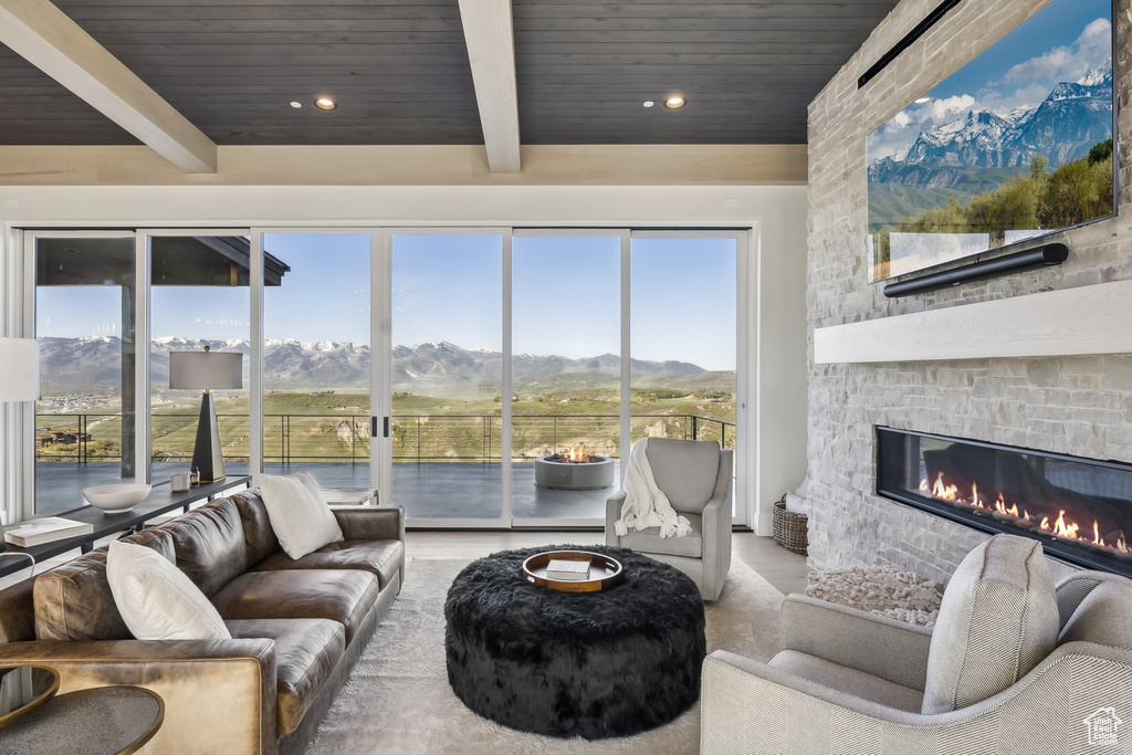 Living area featuring a wooden ceiling with exposed beams, a stone fireplace, and recessed lighting
