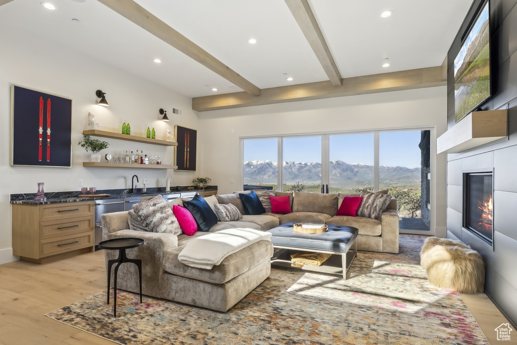 Living room featuring wet bar, beamed ceiling, a mountain view, light wood-style flooring, and recessed lighting