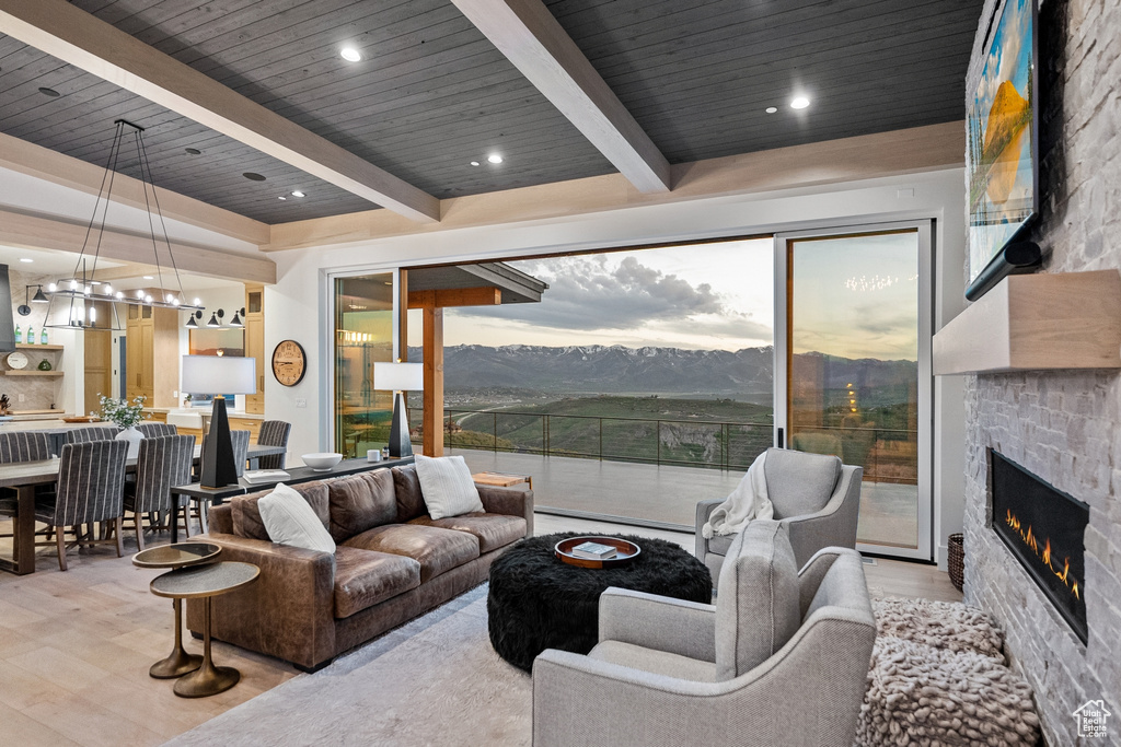 Living room featuring a fireplace, a wooden ceiling with exposed beams, baseboard heating, a chandelier, and wood finished floors
