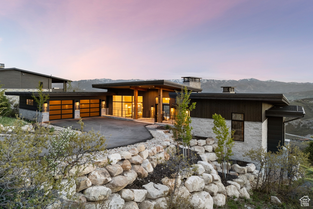 View of front facade with stone siding, a garage, driveway, and a mountain view