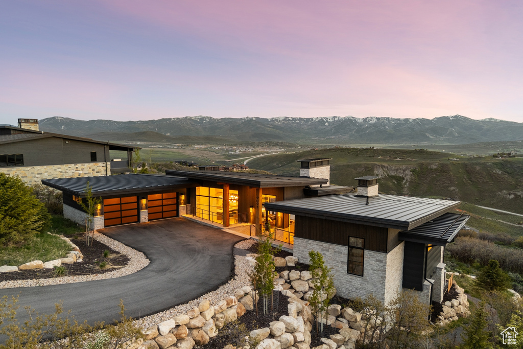 View of front of home featuring a standing seam roof, a chimney, a mountain view, a metal roof, and stone siding