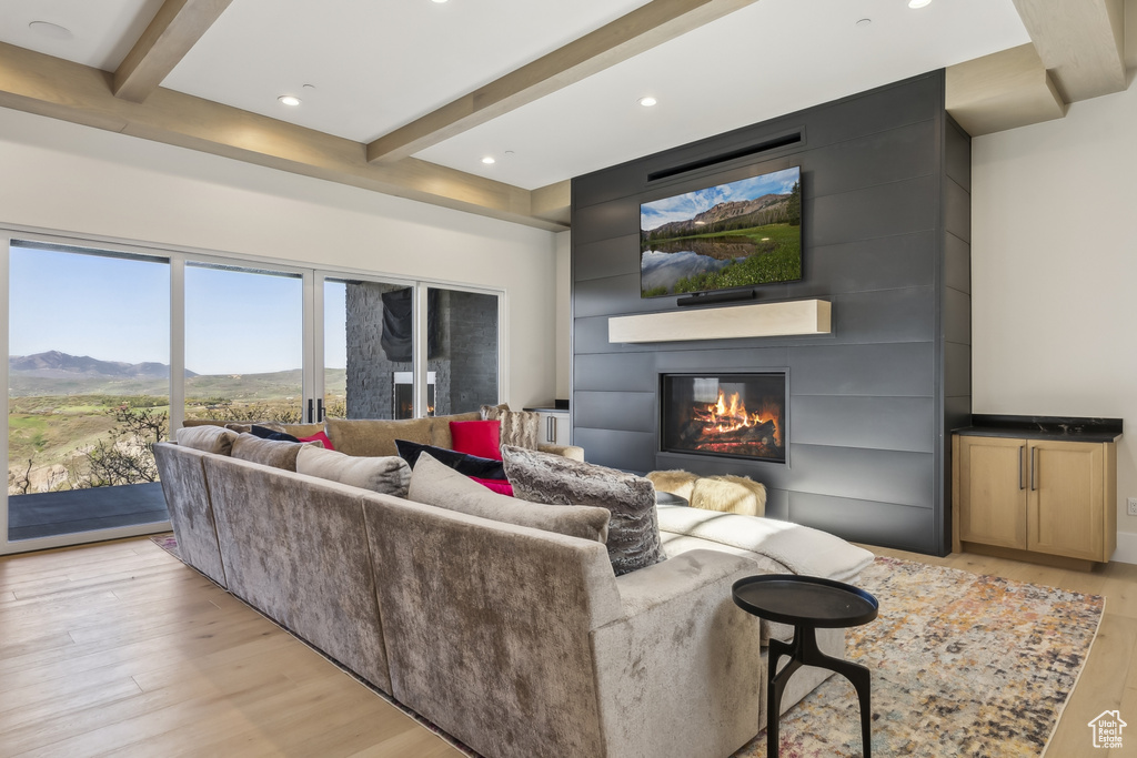 Living area featuring light wood-type flooring, a fireplace, beamed ceiling, a mountain view, and recessed lighting