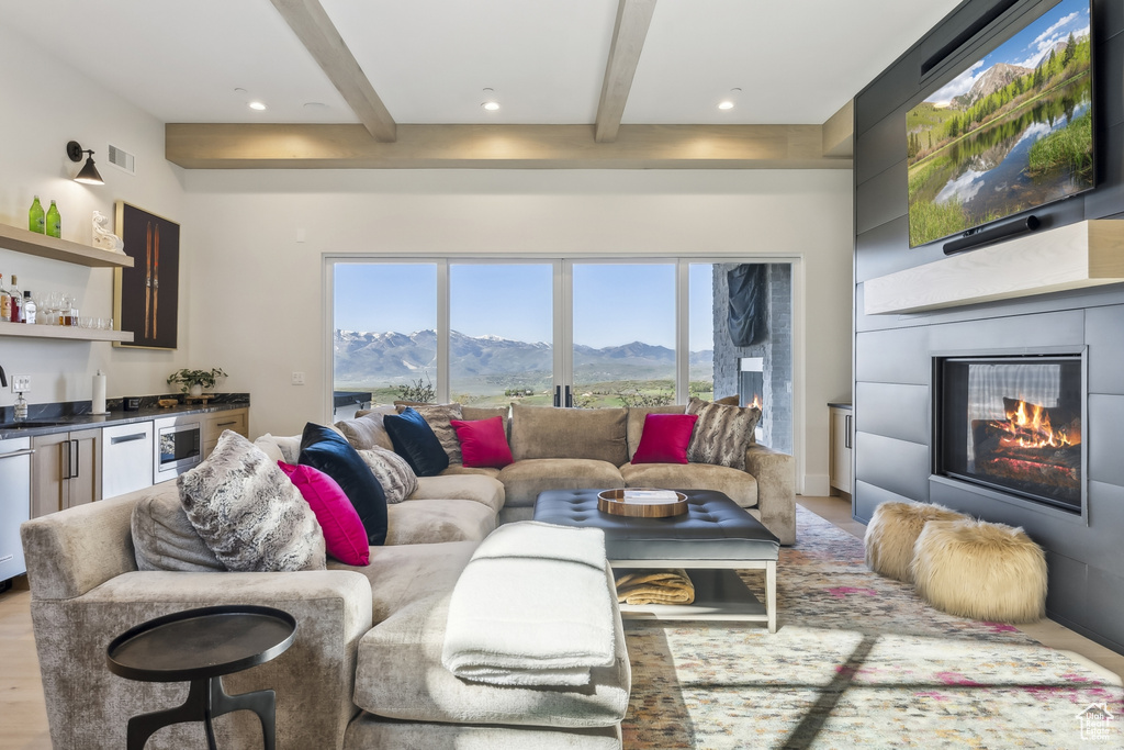 Living area with beamed ceiling, bar with sink, and a fireplace