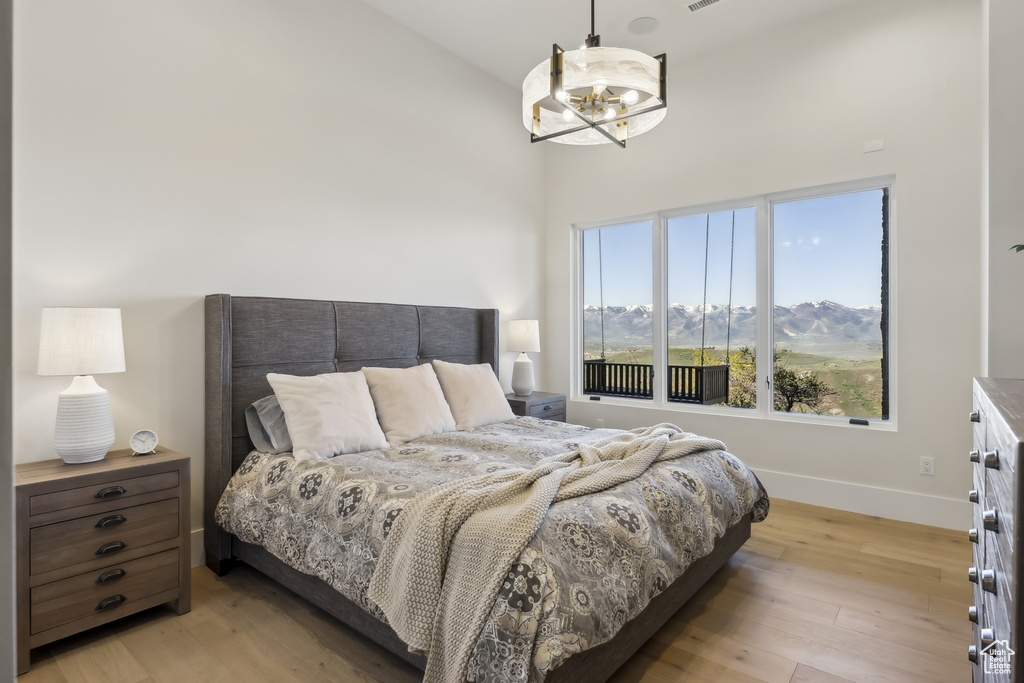 Bedroom featuring light wood-style flooring, a chandelier, and high vaulted ceiling