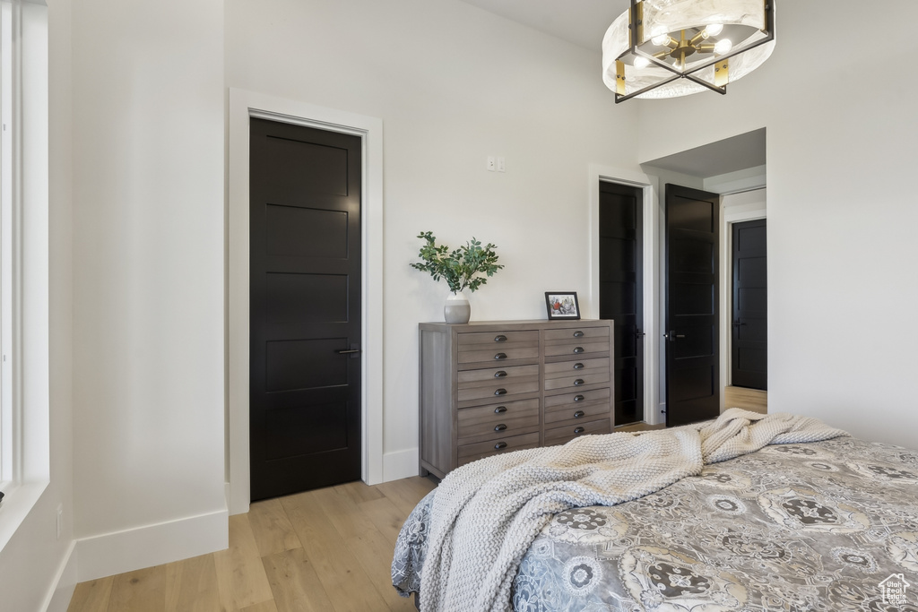 Bedroom featuring light wood-style floors, a chandelier, and a high ceiling