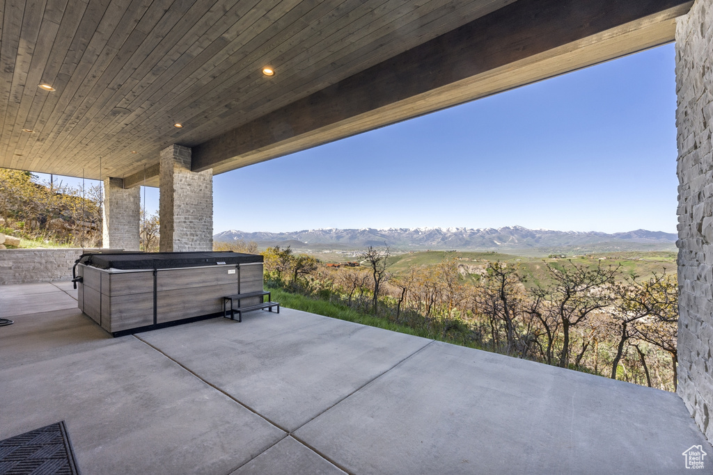 View of patio / terrace with a hot tub and a mountain view