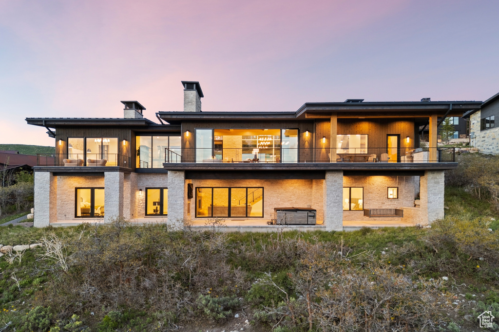 Back of property at dusk with a balcony and a chimney