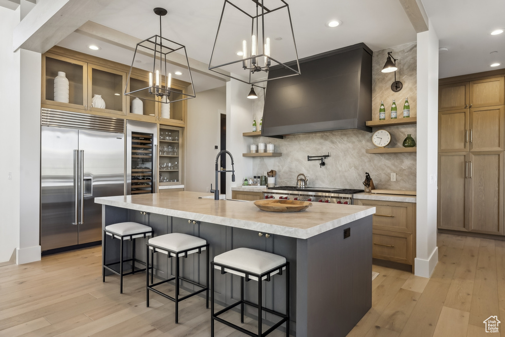 Kitchen featuring stainless steel built in fridge, open shelves, custom exhaust hood, light countertops, and recessed lighting