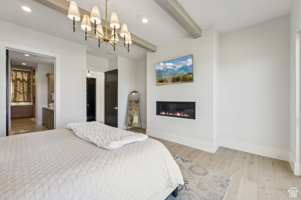 Bedroom with light wood-style flooring, beamed ceiling, a glass covered fireplace, a chandelier, and recessed lighting