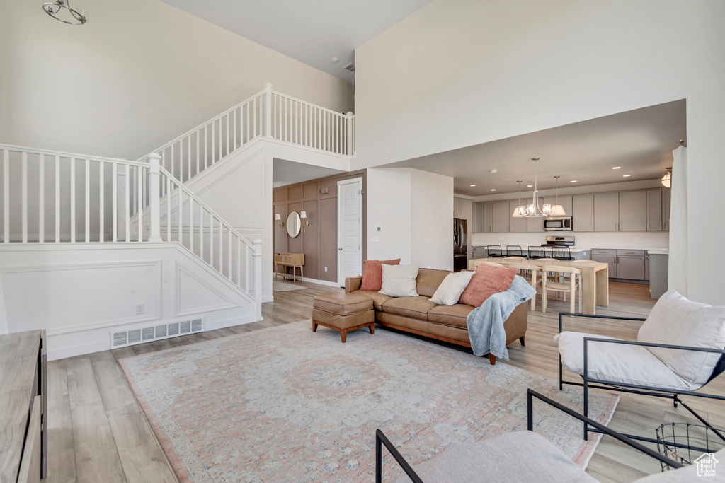 Living area featuring light wood-type flooring, stairs, a towering ceiling, a chandelier, and recessed lighting