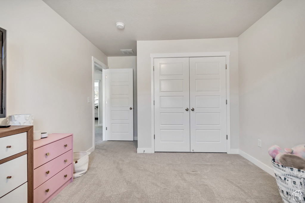 Bedroom featuring light carpet, baseboards, and a closet