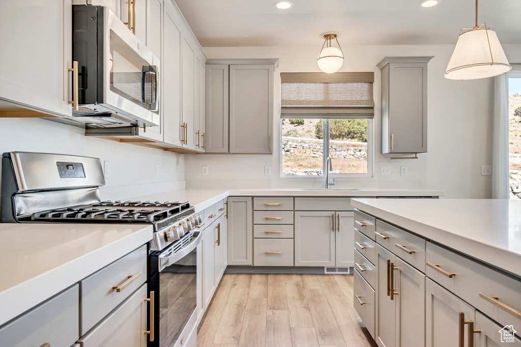 Kitchen with appliances with stainless steel finishes, gray cabinetry, a sink, recessed lighting, and light countertops