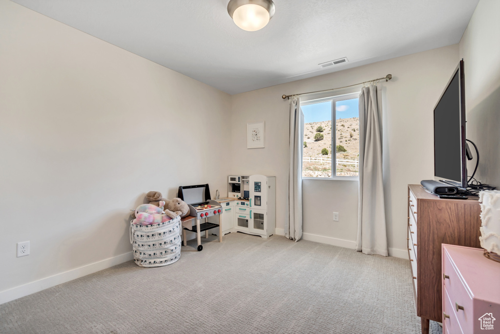 Living area featuring baseboards, light carpet, and a desk