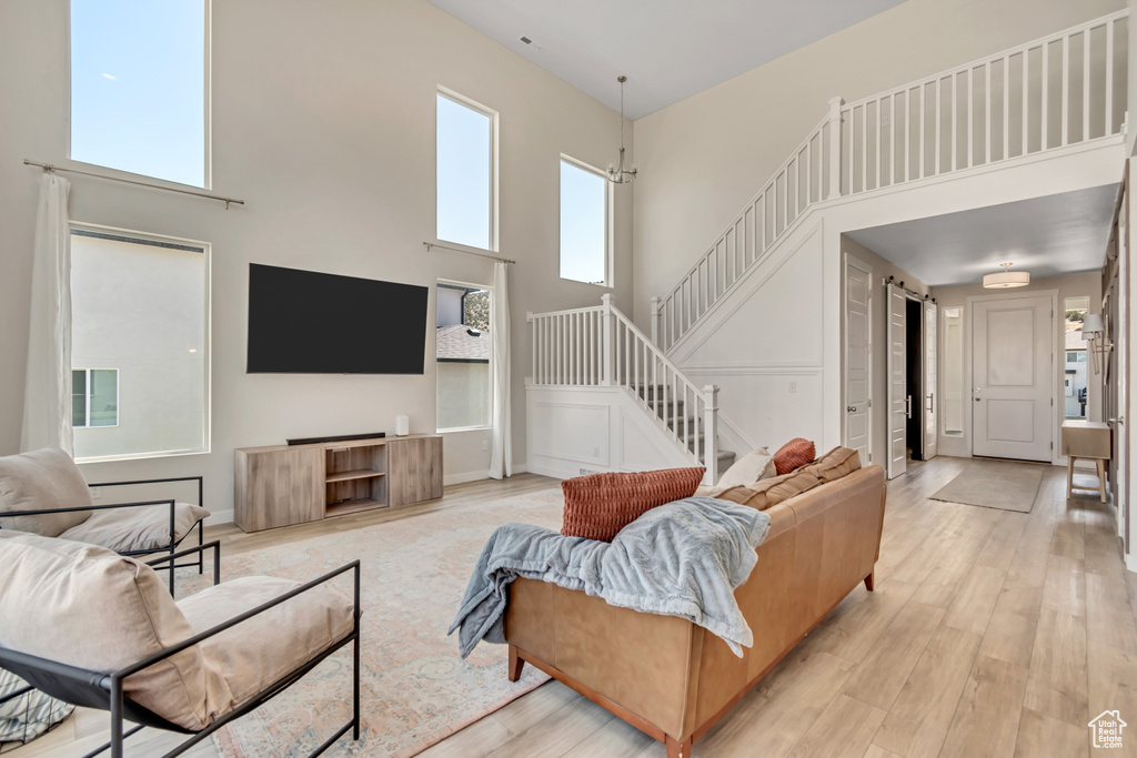 Living area with a high ceiling, stairs, and light wood finished floors