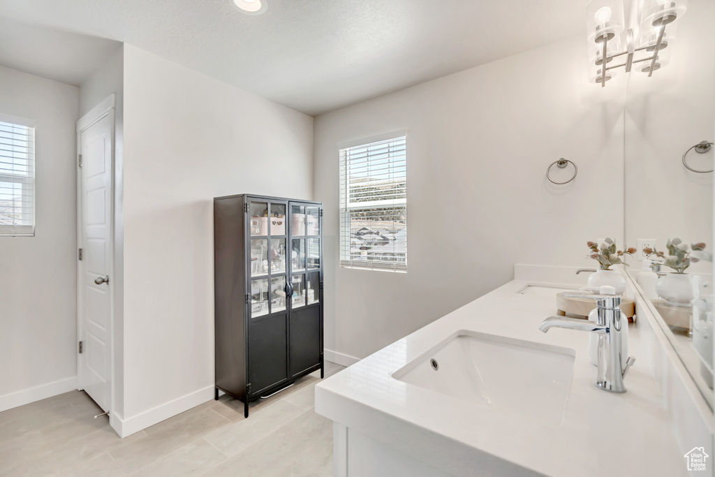 Full bath with double vanity, baseboards, a chandelier, and tile patterned flooring