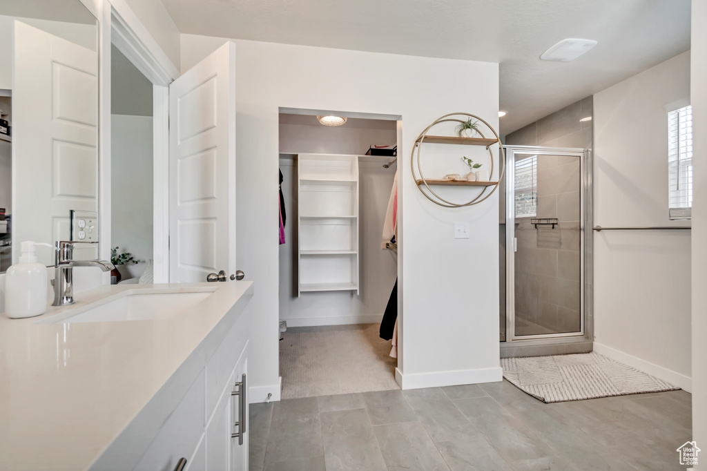 Bathroom with vanity, a shower stall, a spacious closet, and baseboards