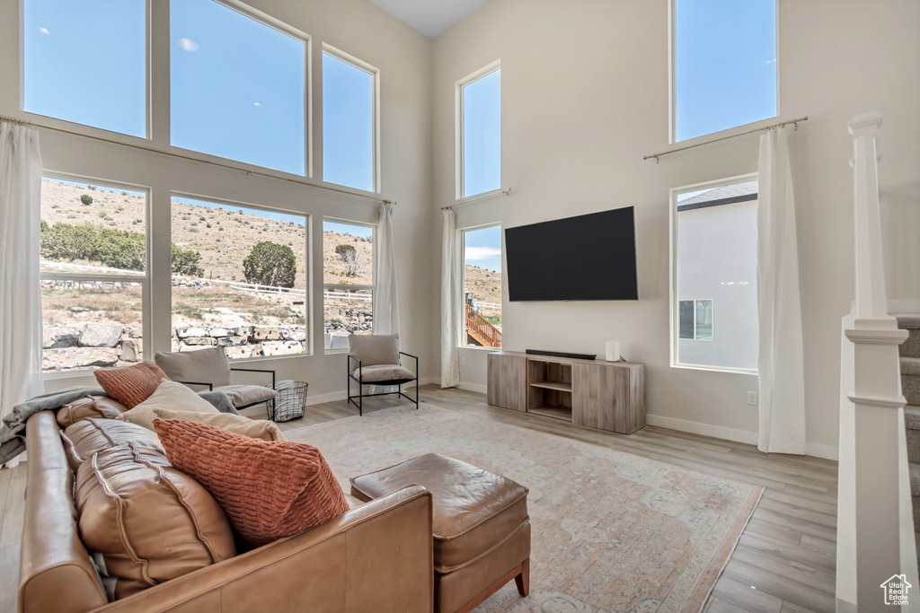 Living area featuring a towering ceiling, wood finished floors, and baseboards