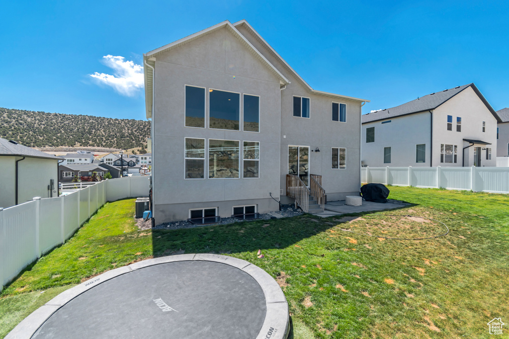 Rear view of property featuring stucco siding, cooling unit, and a residential view