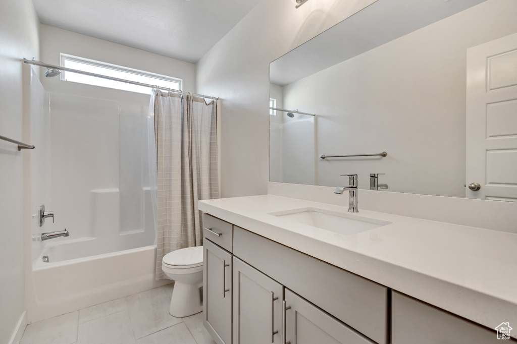Full bathroom featuring shower / tub combo, toilet, vanity, and tile patterned flooring