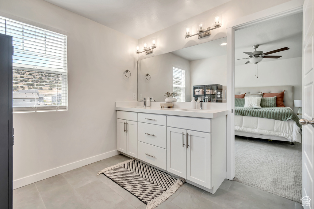 Bathroom with connected bathroom, double vanity, ceiling fan, baseboards, and tile patterned flooring