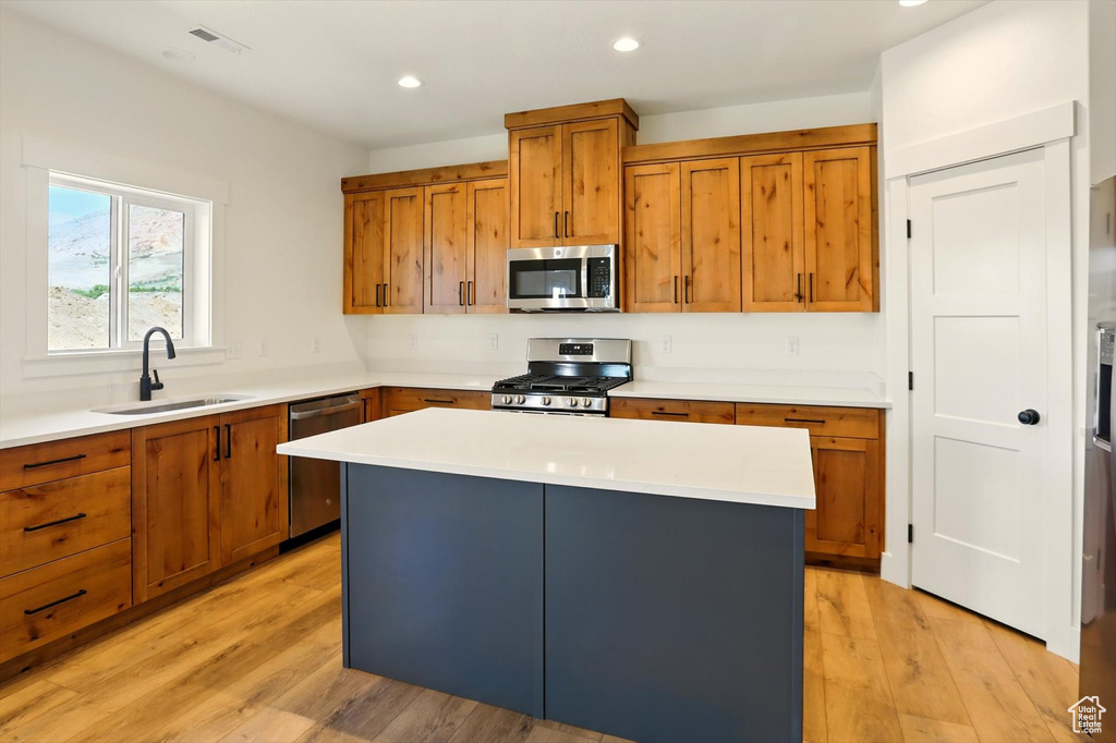 Kitchen with stainless steel appliances, brown cabinets, light wood-style floors, light countertops, and recessed lighting