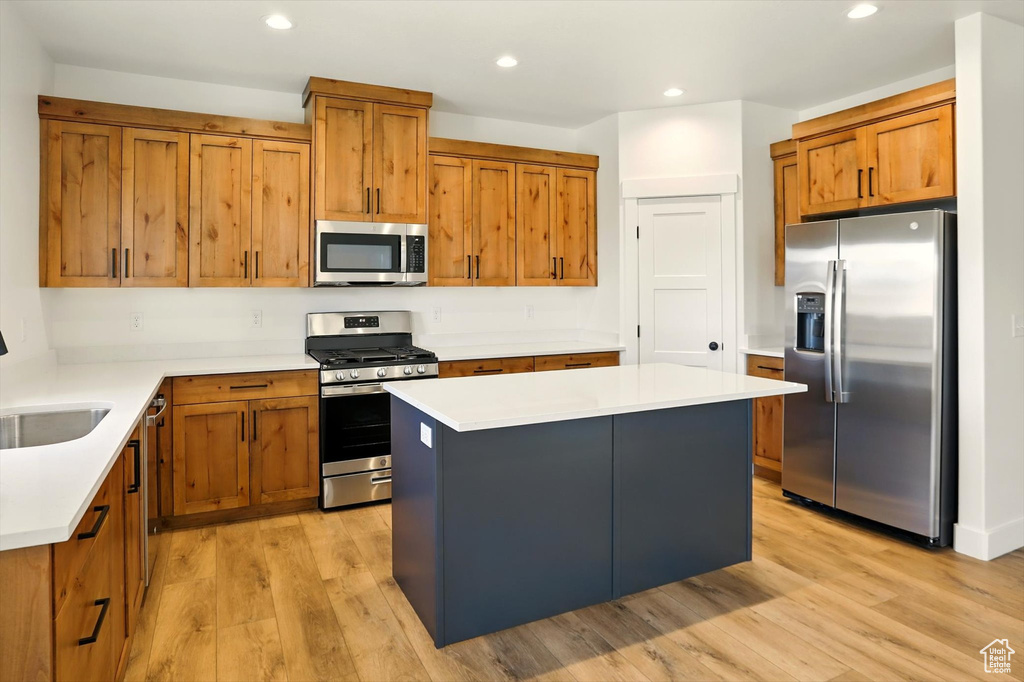 Kitchen featuring stainless steel appliances, light wood-style flooring, brown cabinetry, a kitchen island, and recessed lighting