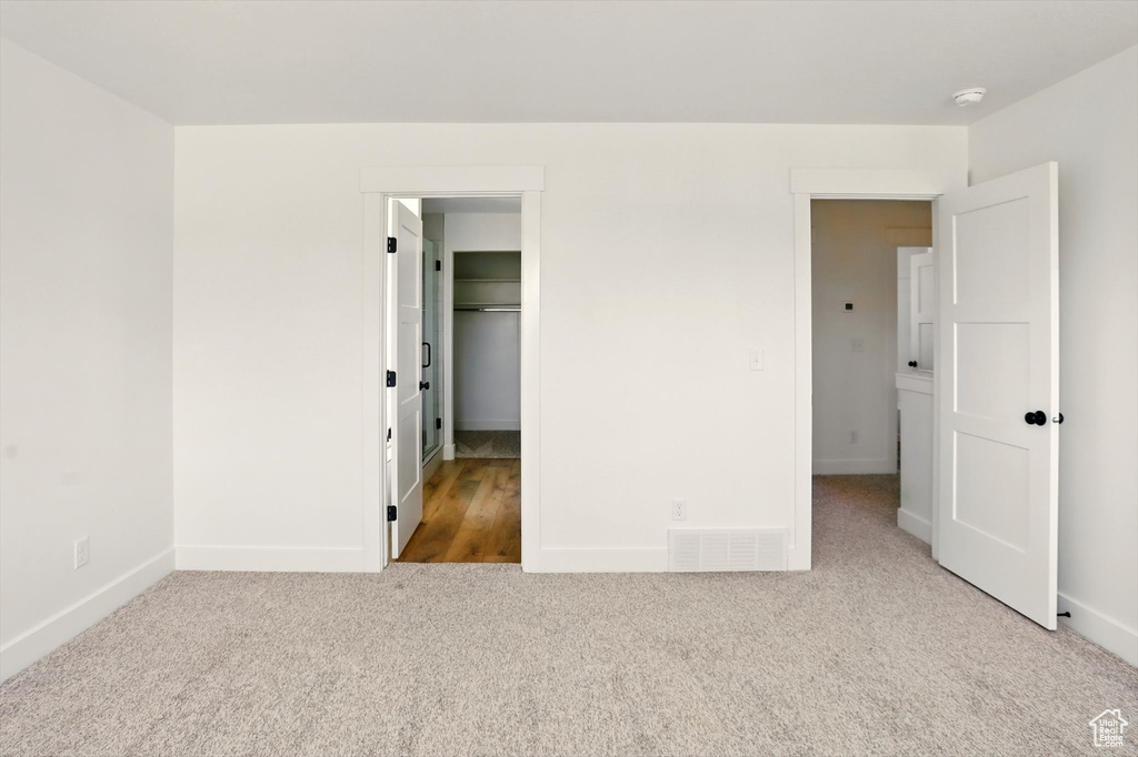 Unfurnished bedroom featuring carpet floors and a walk in closet